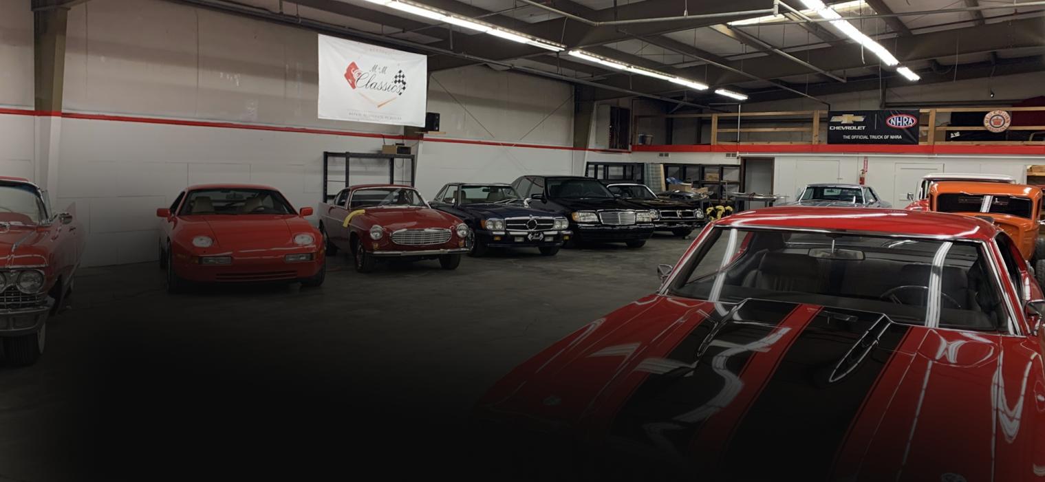 A red car showroom with multiple vehicles on display. A sign hangs from the ceiling.