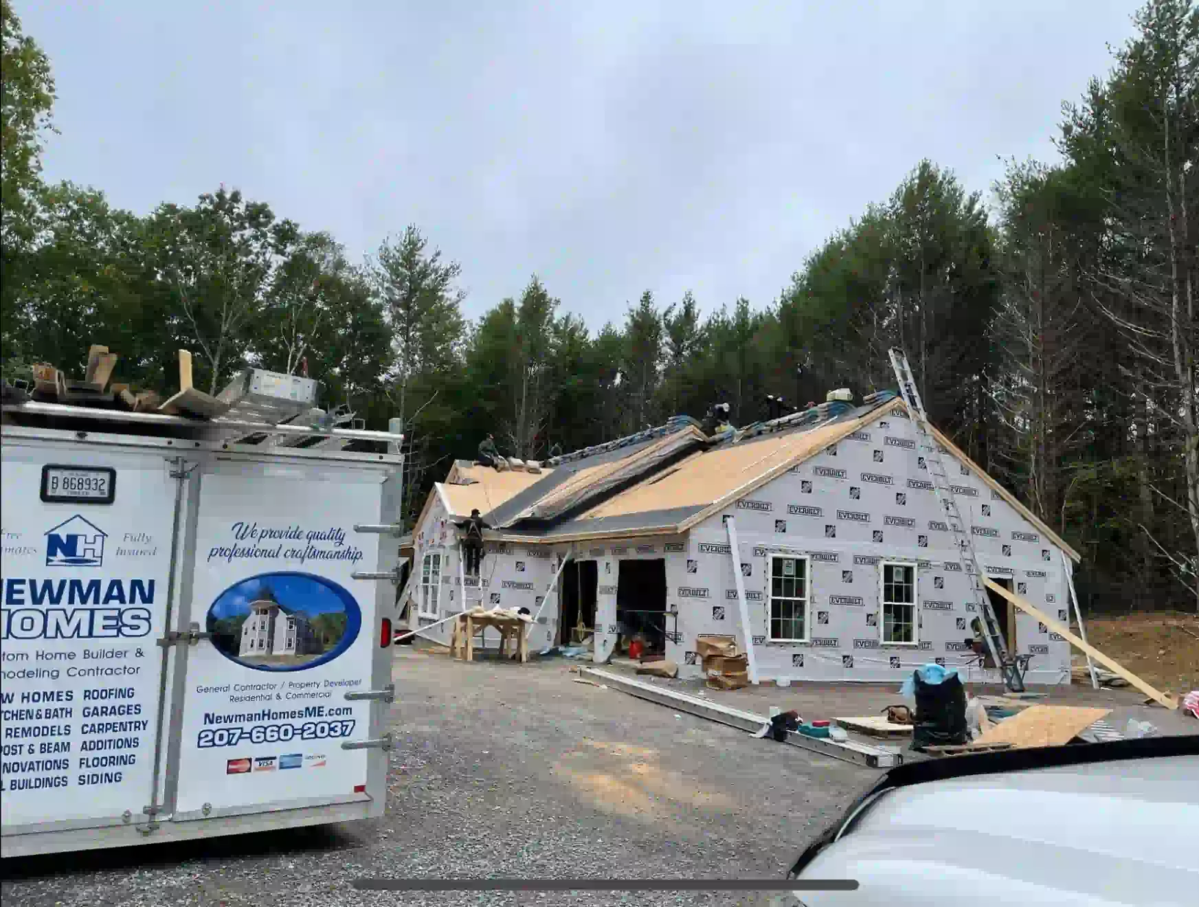 A newman homes trailer is parked in front of a house under construction.