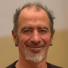 A man with a beard and earrings is smiling for the camera