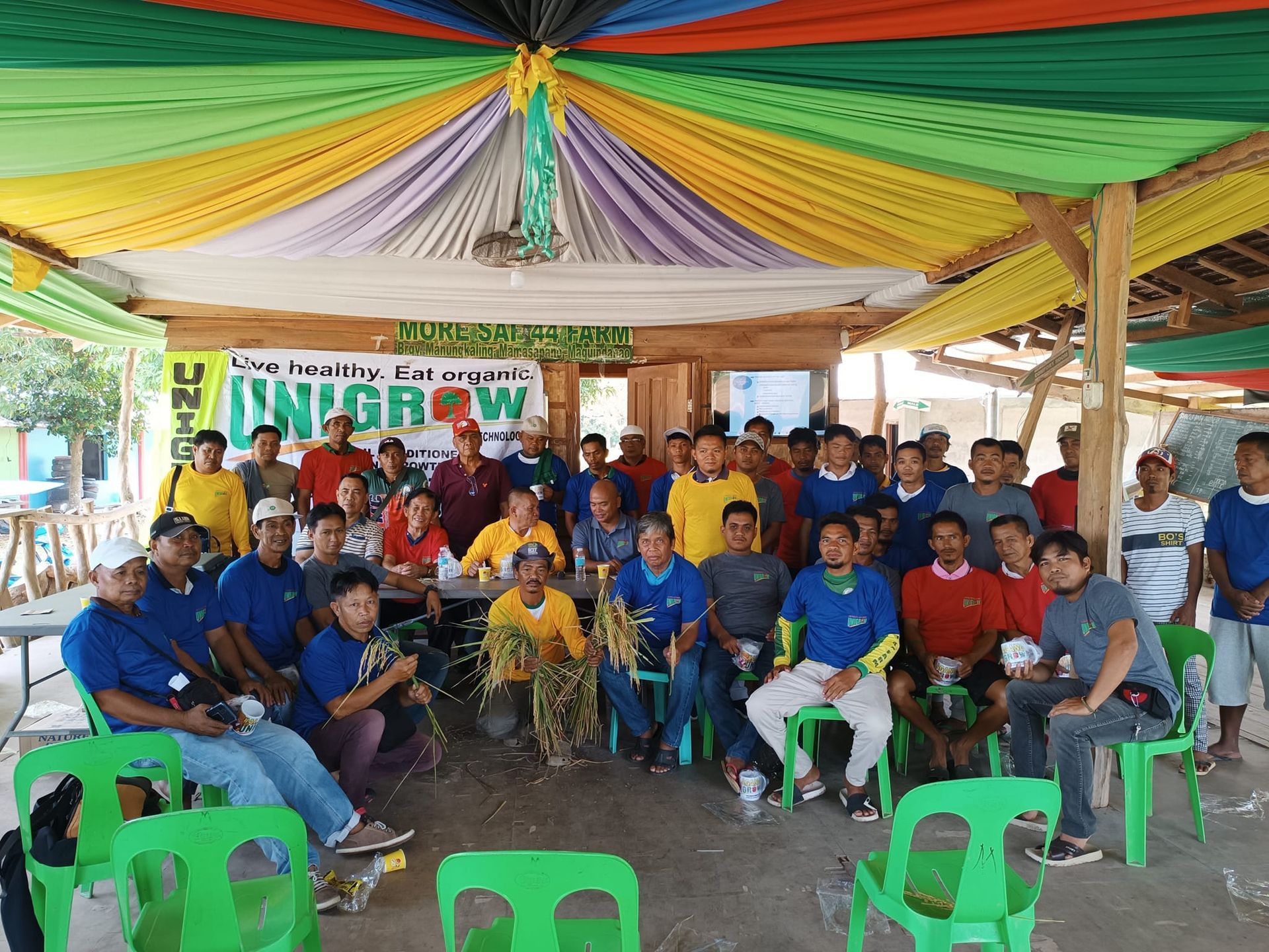 A group of people are sitting in chairs under a tent.