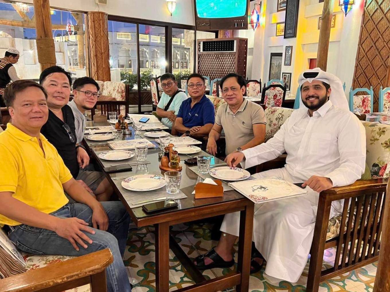 A group of men are sitting around a table in a restaurant.