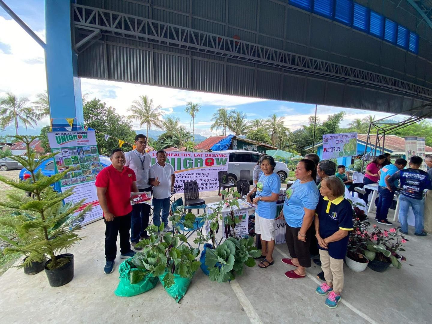 A group of people are standing around a table with potted plants.