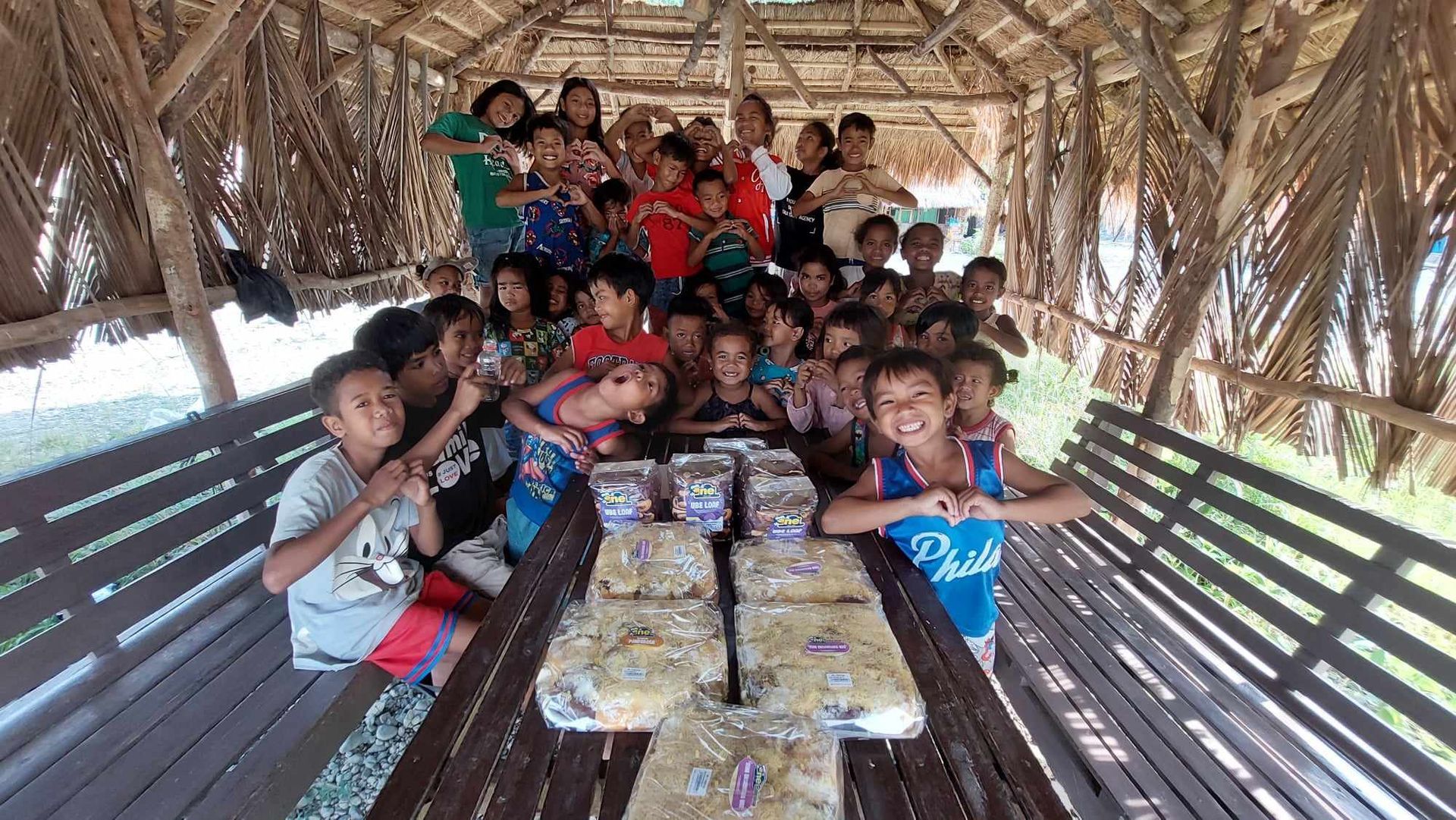 A group of children are posing for a picture in a hut.