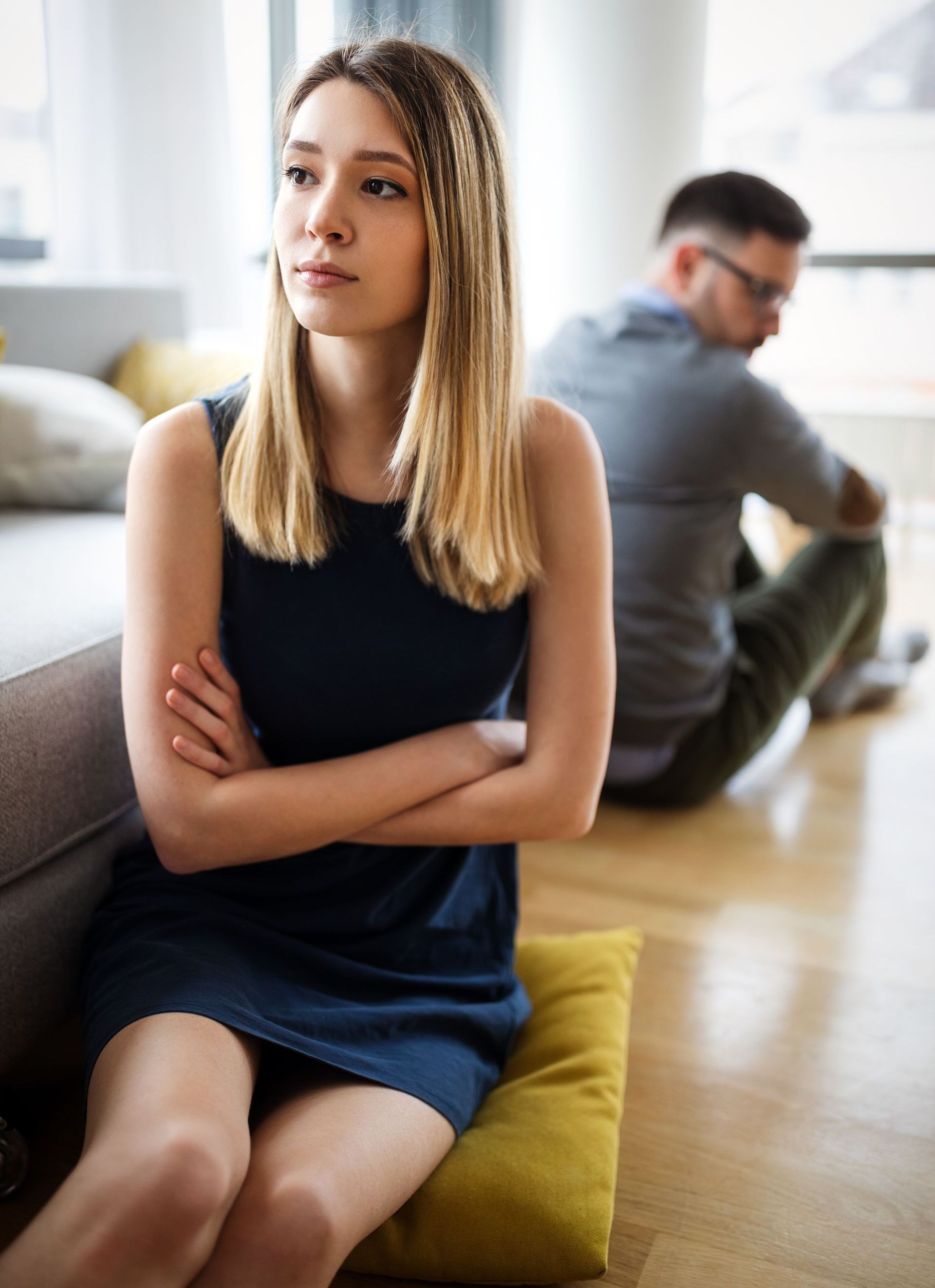 A woman is sitting on a pillow in front of a man sitting on the floor.