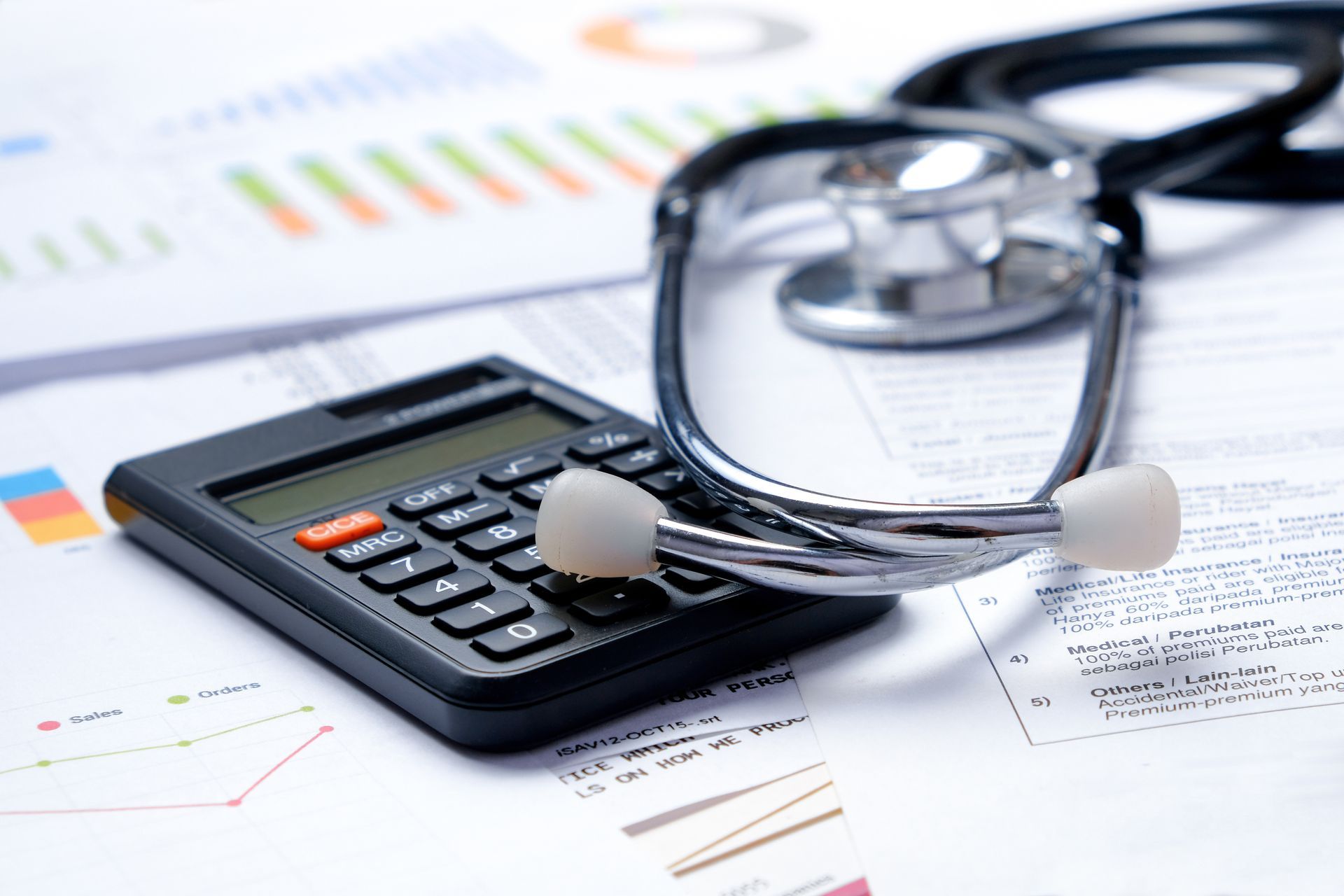 Calculator, stethoscope, and eyeglasses on financial reports, suggesting healthcare budgeting or billing