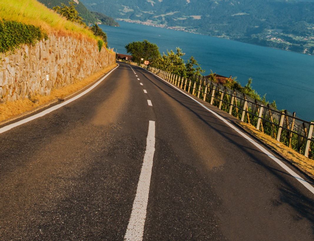La route serpente à flanc de colline, offrant une vue sur le lac sur la droite.