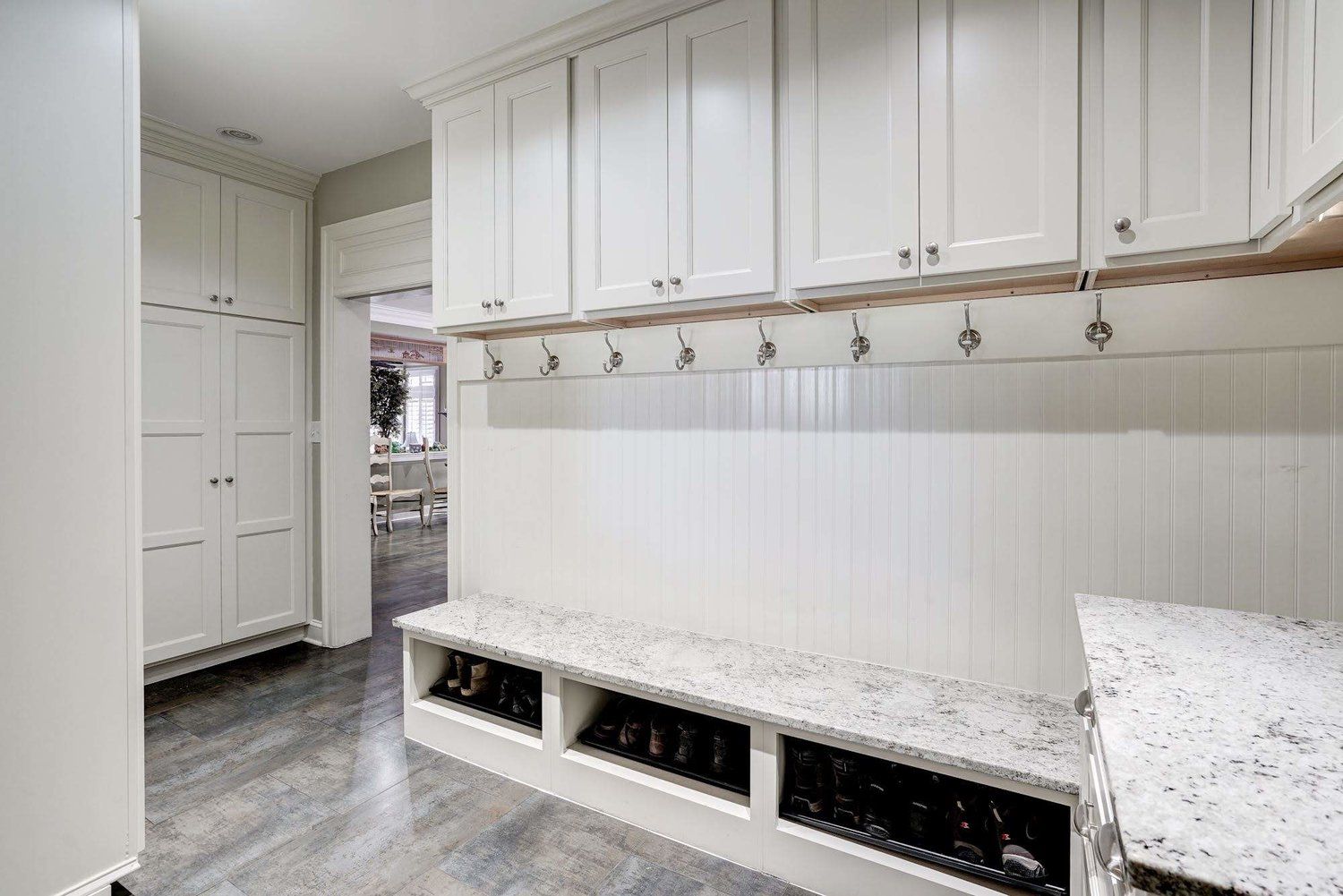 A mud room with white cabinets and a bench.