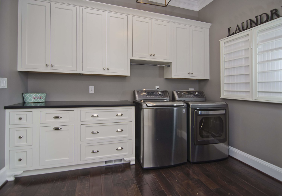 A laundry room with stainless steel appliances and white cabinets