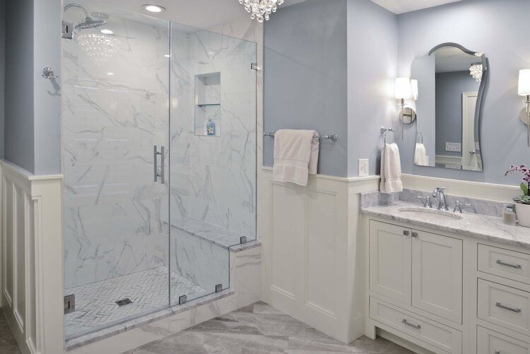 A bathroom with a walk in shower , sink and mirror.