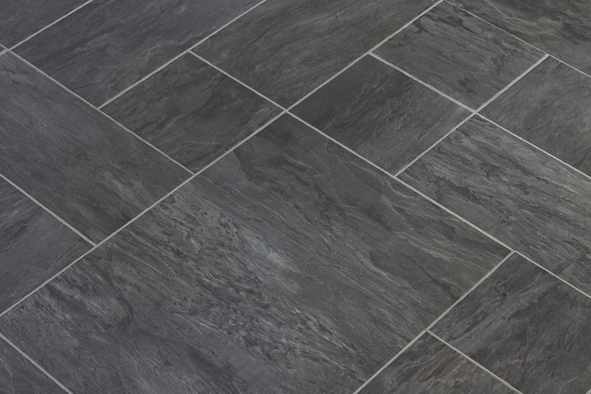 A close up of a black tile floor with white grout.