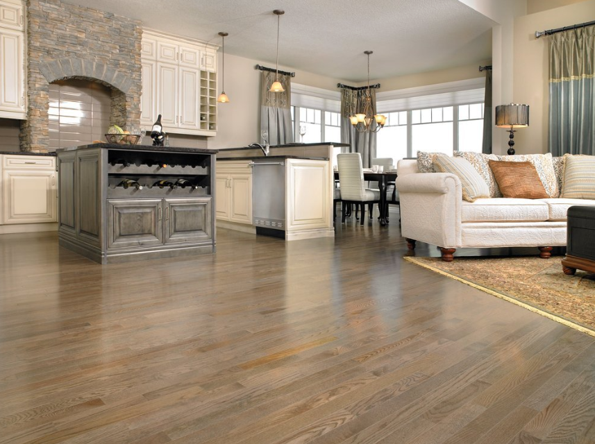 A living room filled with furniture and a kitchen with hardwood floors.