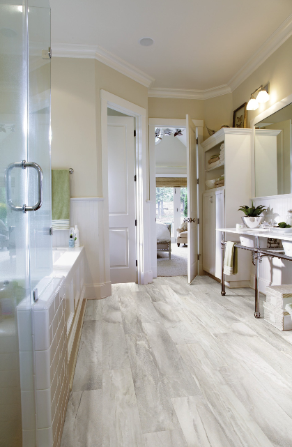 A bathroom with a bathtub , sink , mirror and hardwood floor.