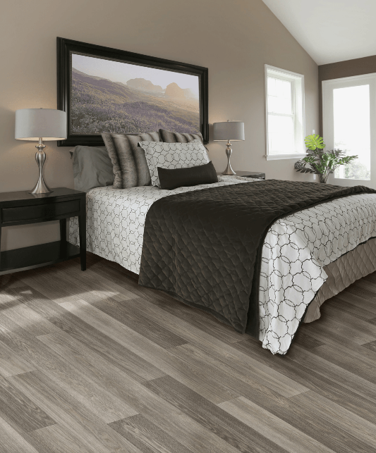 A bedroom with a large bed and a picture on the wall above it.