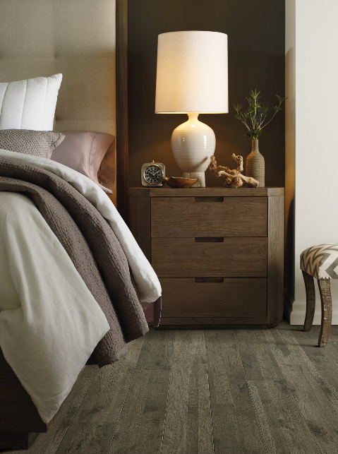 A bedroom with a lamp on a nightstand next to a bed