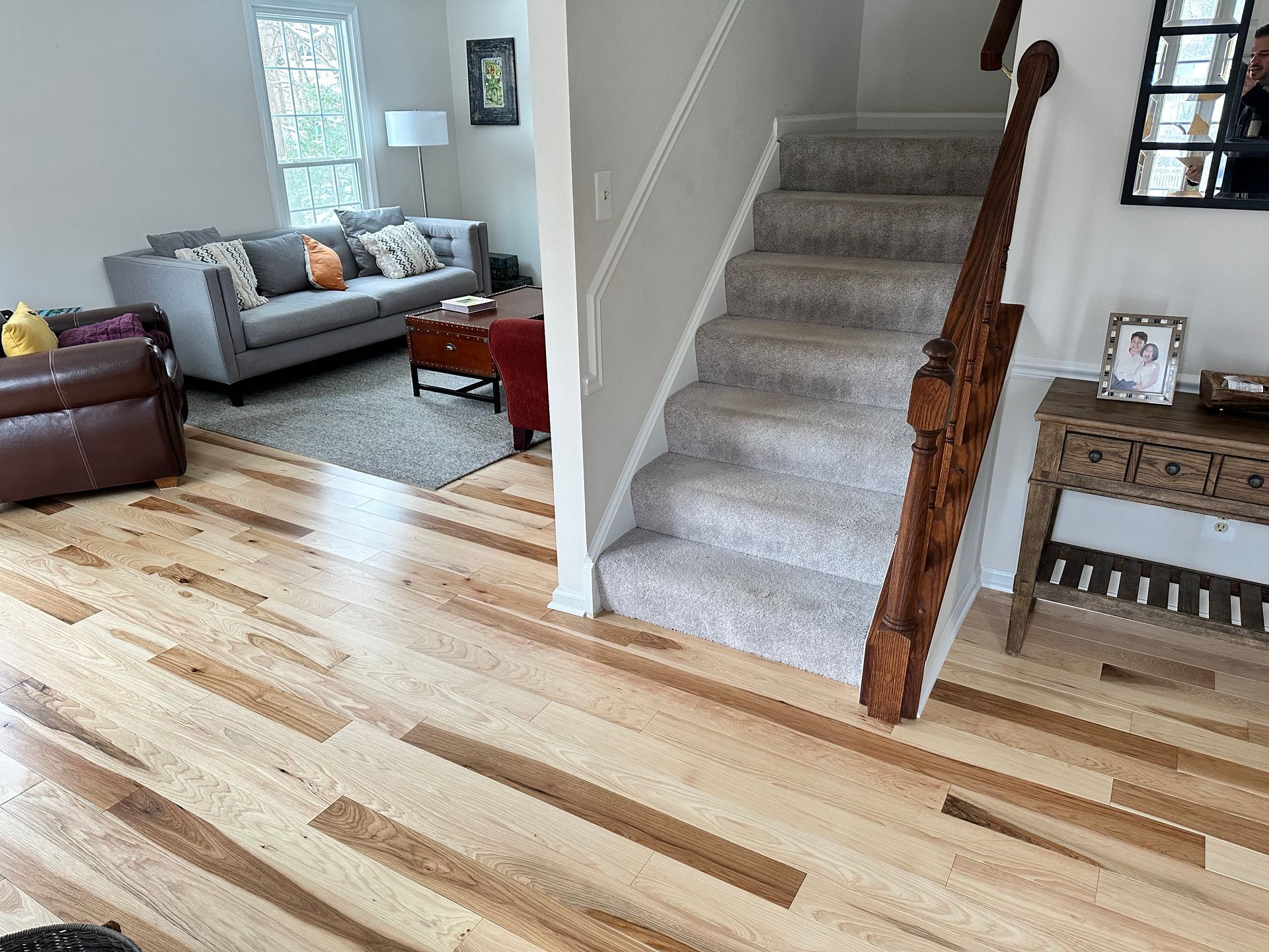 A living room with hardwood floors and stairs leading up to the second floor.