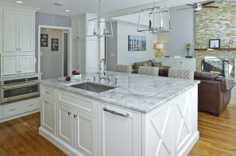 A kitchen with white cabinets , granite counter tops , and a large island.