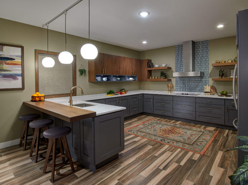 A kitchen with a large island , stools , a sink and a refrigerator.