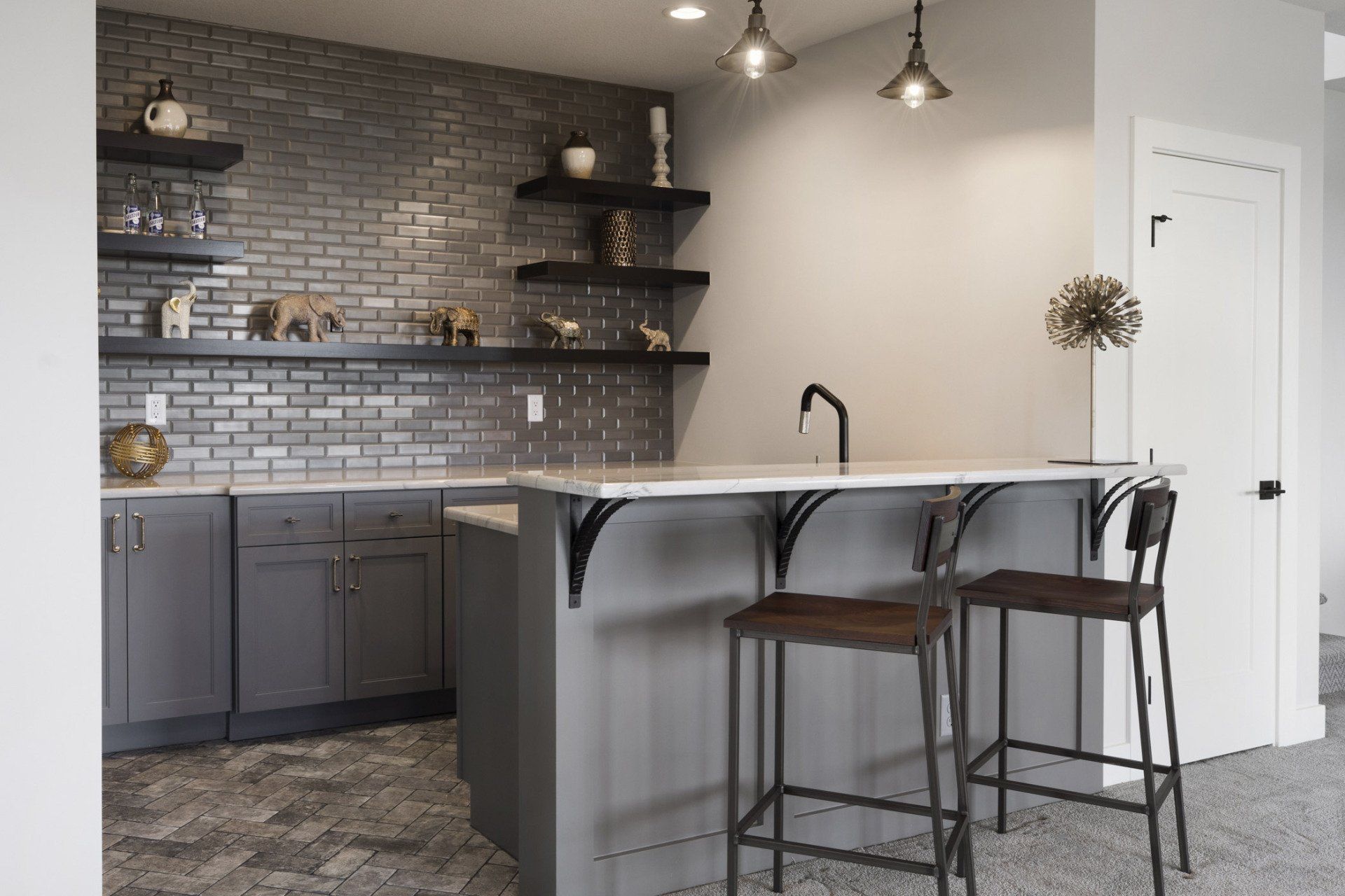 A kitchen with a bar and stools and a brick wall.