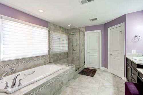 A bathroom with purple walls , a bathtub , a sink , and a walk in shower.