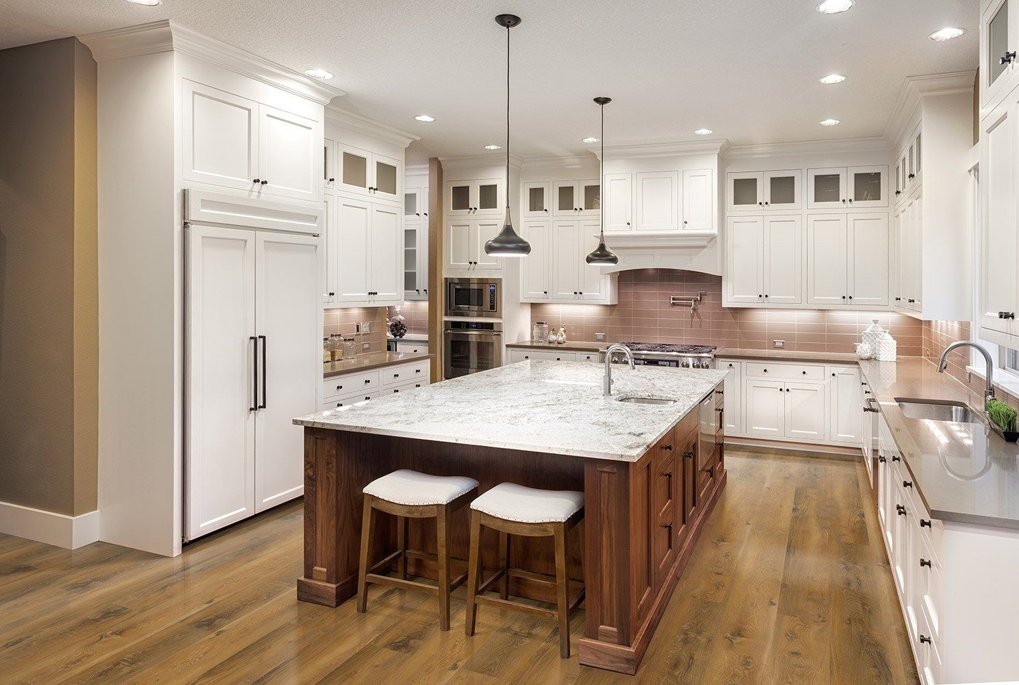 A kitchen with white cabinets and a large island in the middle.