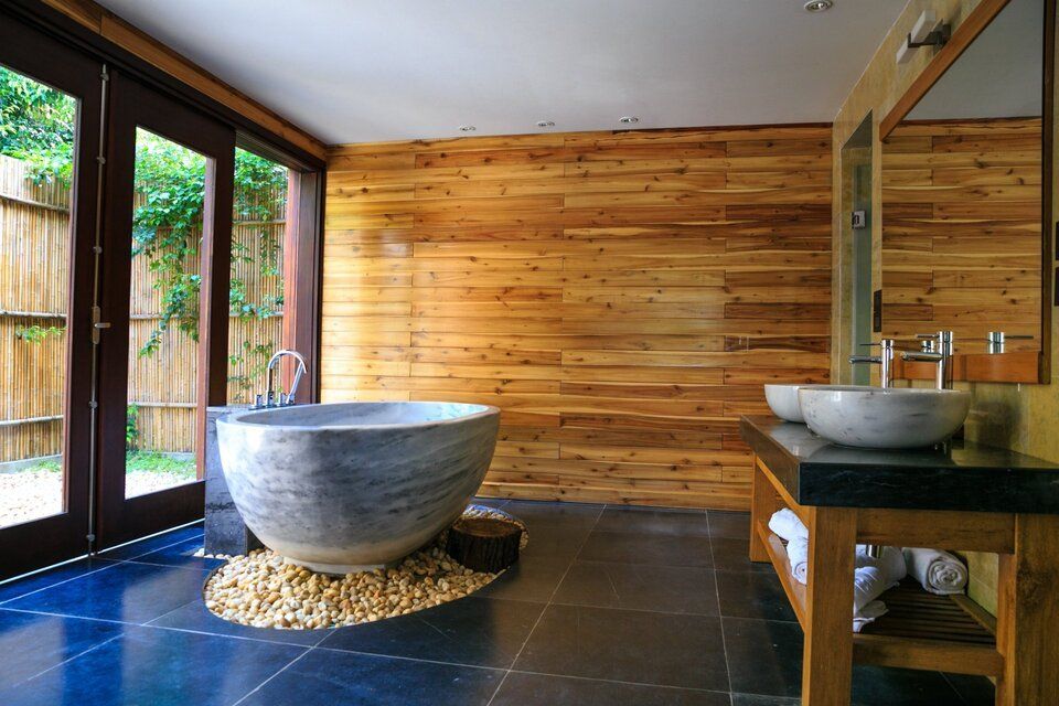 A bathroom with a bathtub , sinks , and wooden walls.