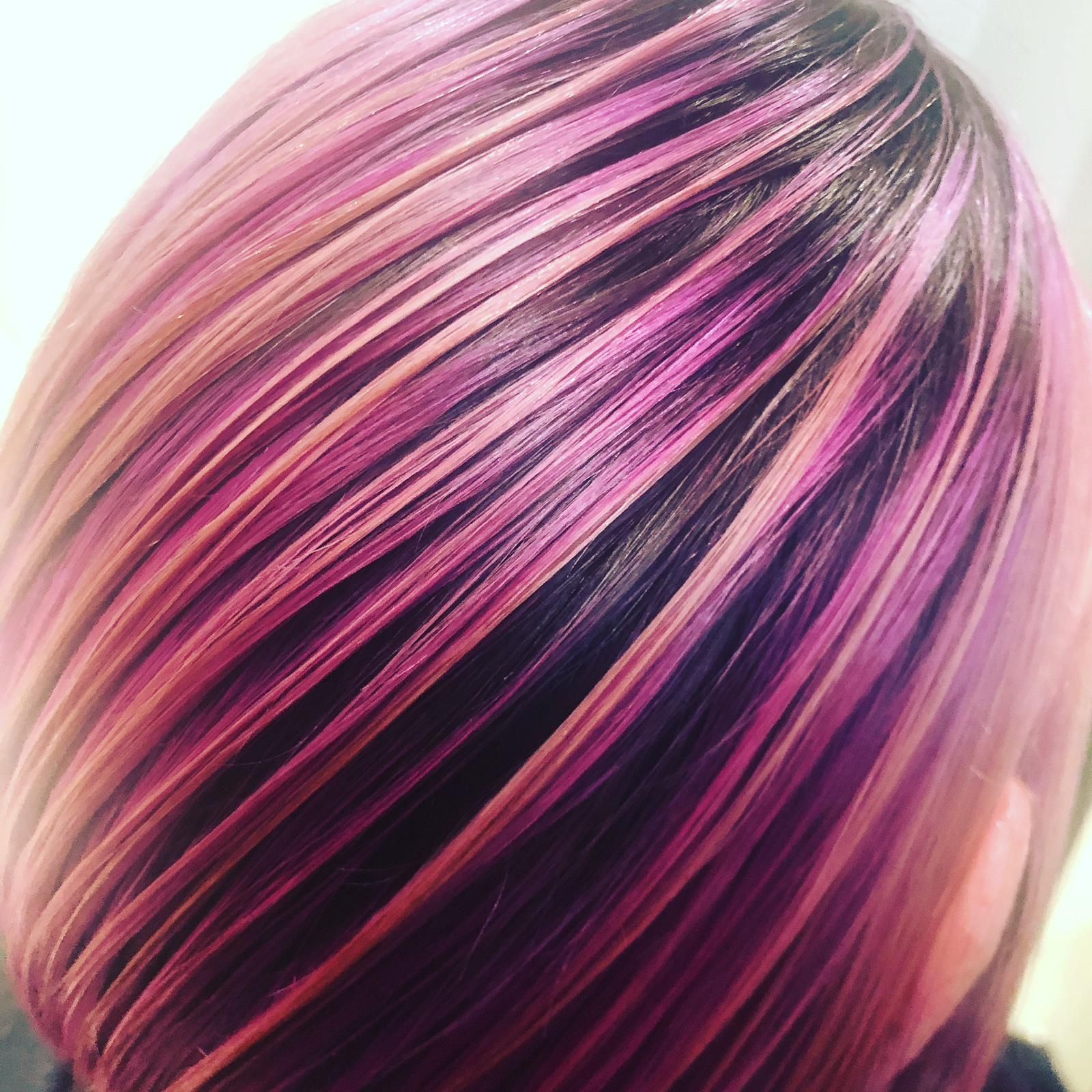 Close-up of short hair with pink, purple, and blonde highlights, styled in a smooth layered bob