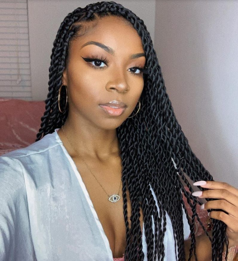 A woman with braids and a necklace is taking a selfie.