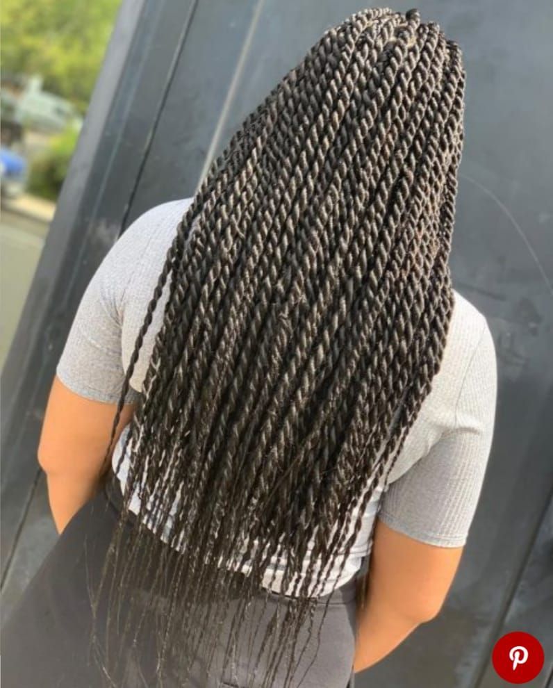 A woman with long braids is wearing a gray shirt and black pants.