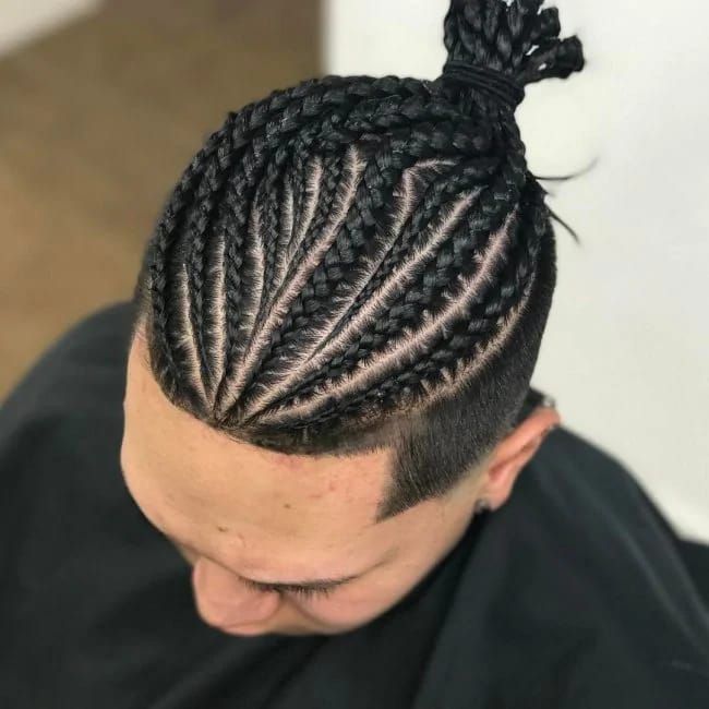 A man with braids in his hair is wearing a black cape