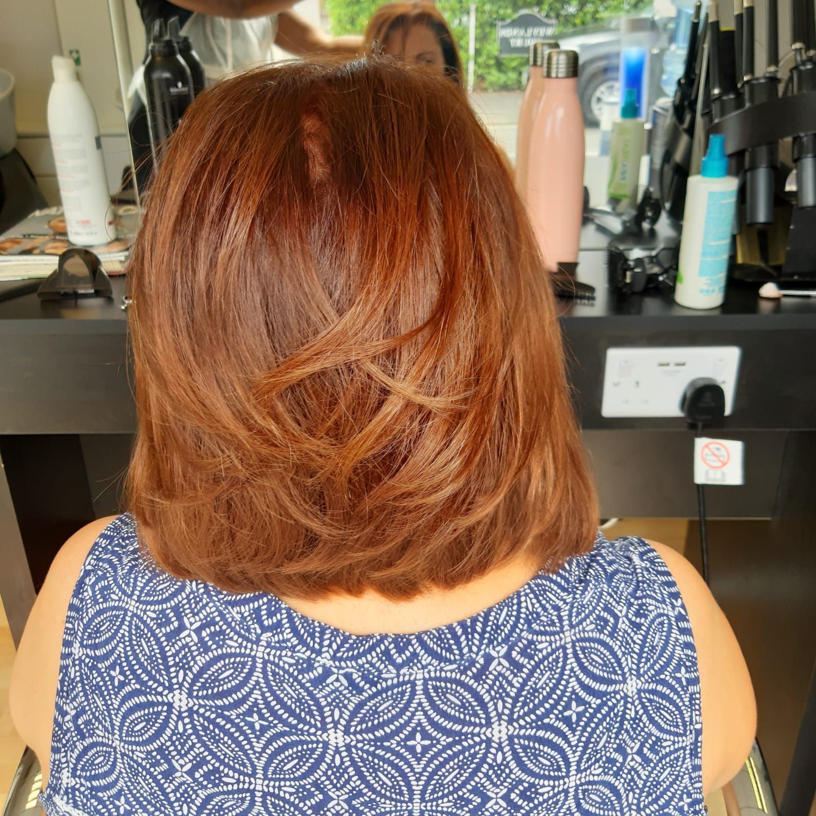 A woman with red hair is sitting in front of a mirror