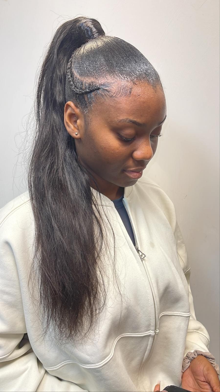 A woman is wearing a white jacket and a ponytail.