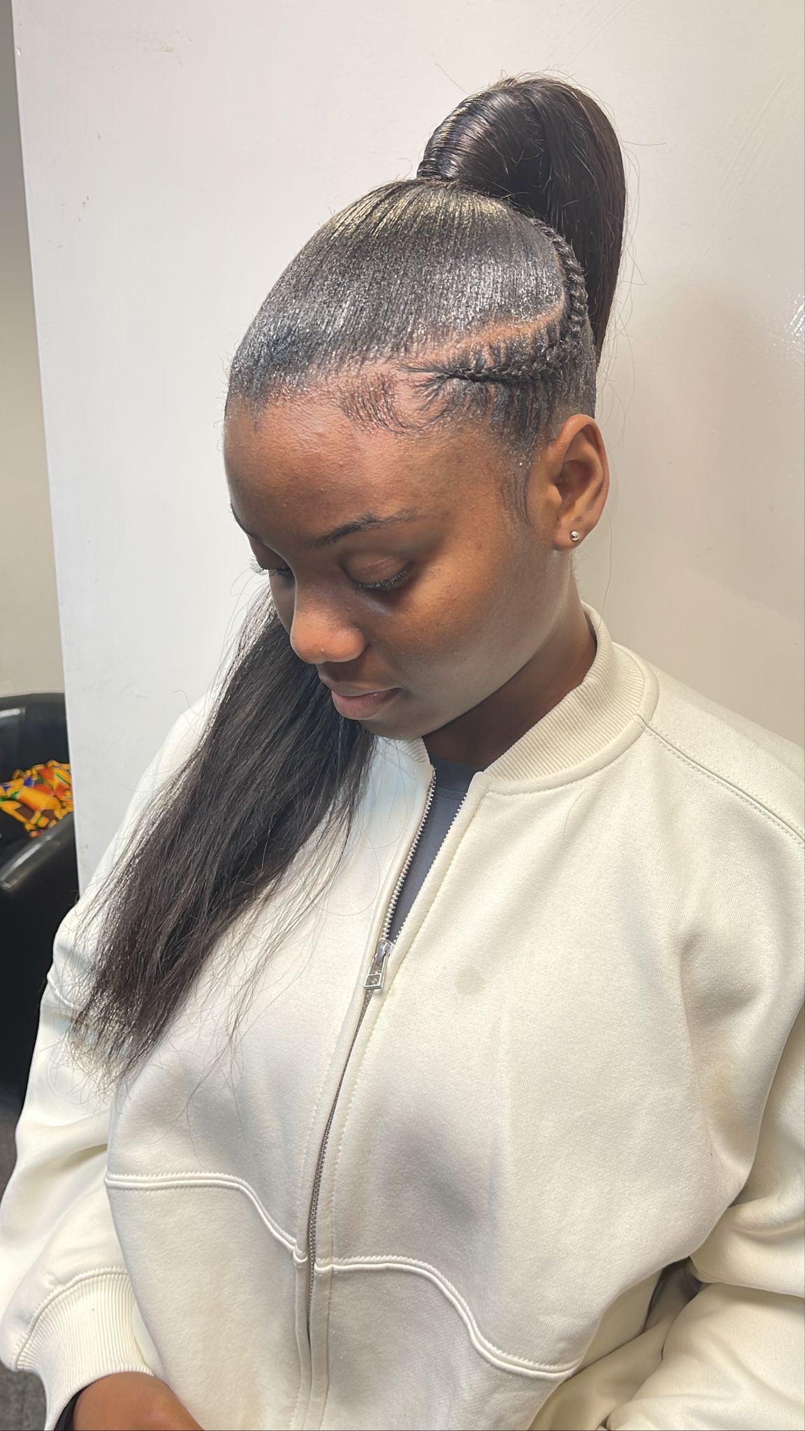 A woman is wearing a white jacket and a ponytail.