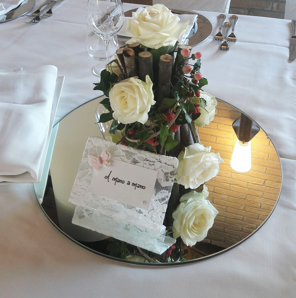 Rose bianche e un segnaposto su un centrotavola a specchio in una sala da pranzo formale.
