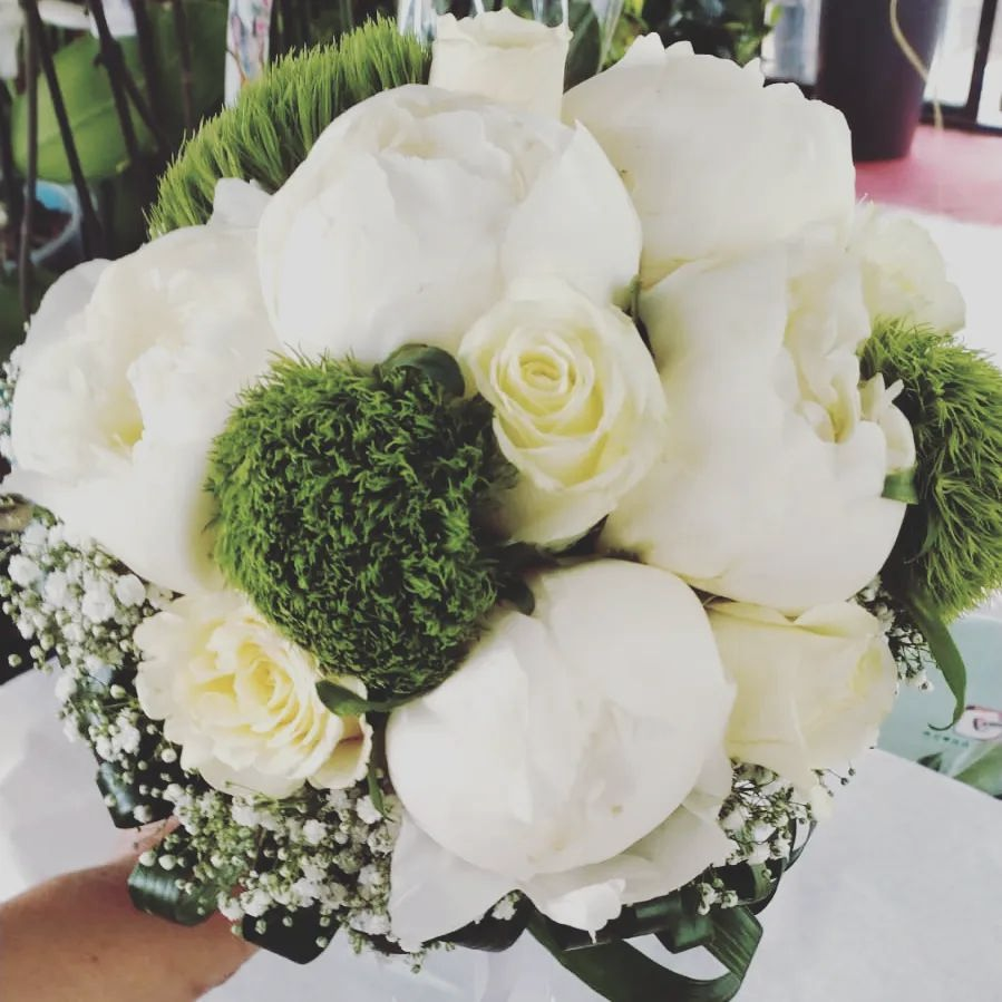Bouquet di rose bianche con fiori verdi di contorno e gypsophila, disposto in una composizione rotonda in stile nuziale.