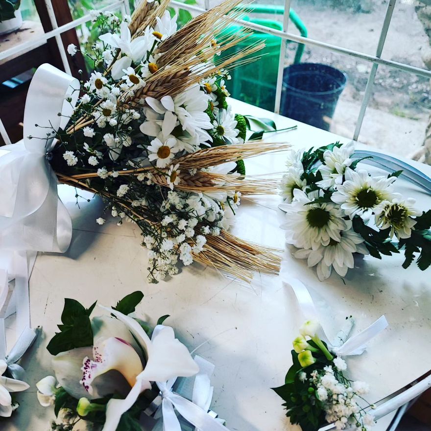 Mazzi di fiori bianchi con steli di grano disposti su un tavolo in una stanza luminosa