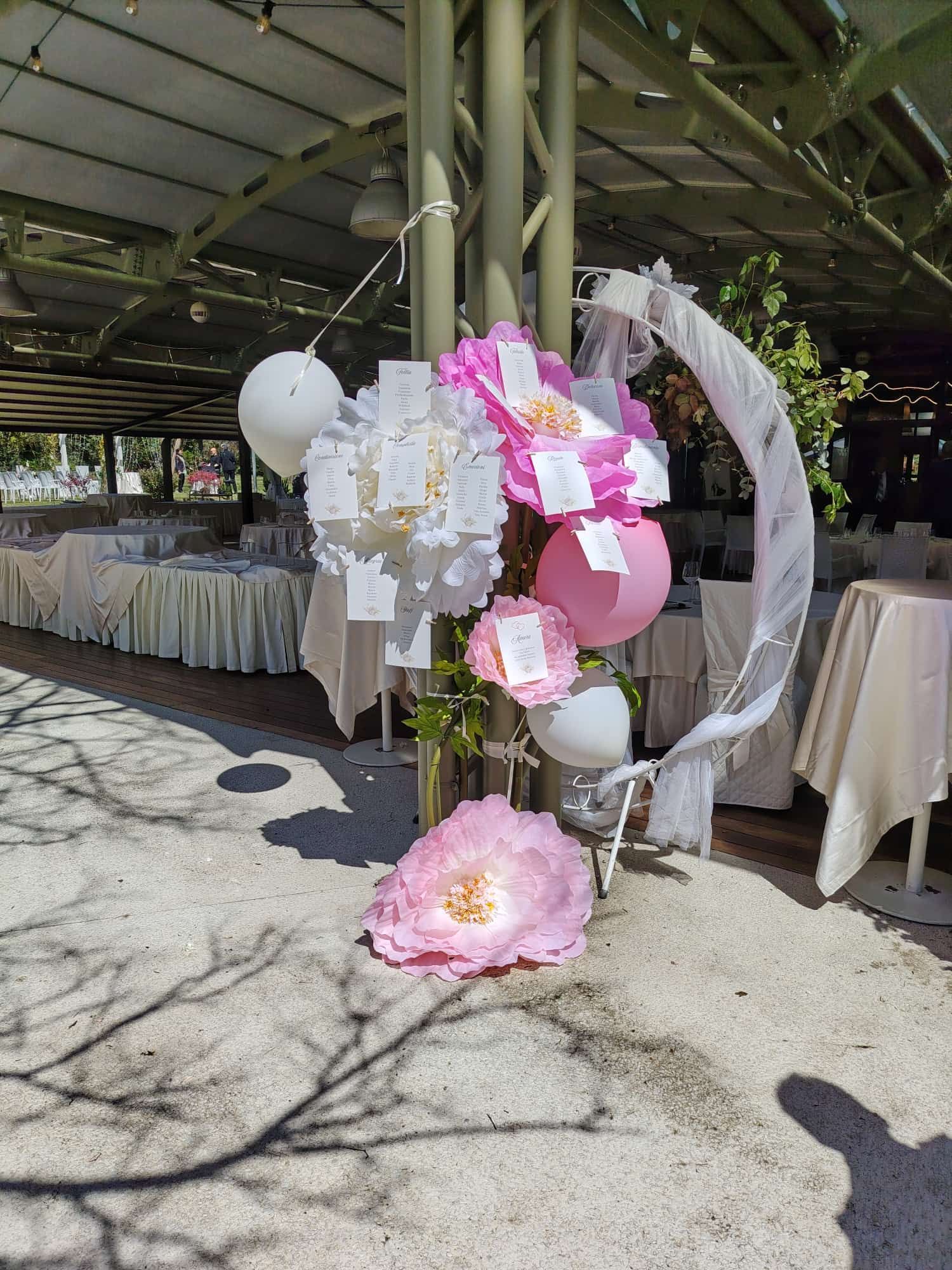 Decorazione con palloncini rosa e bianchi all'ingresso del tendone per eventi all'aperto.