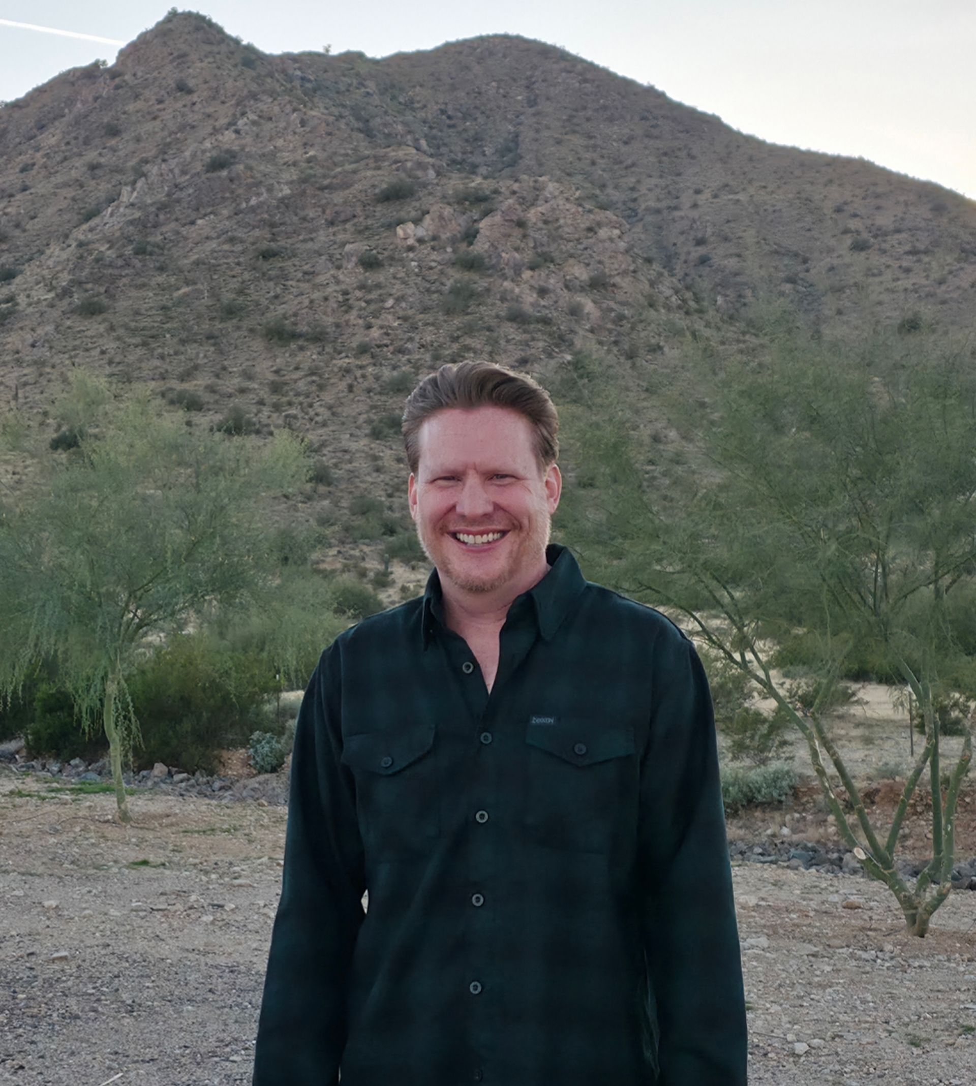 Aaron, founder of Artificial Grass Queen Creek, stands in front of San Tan Mountains