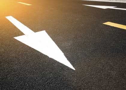 White arrow painted on dark asphalt road, indicating direction.
