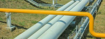 Yellow and gray industrial pipes on a grassy field.