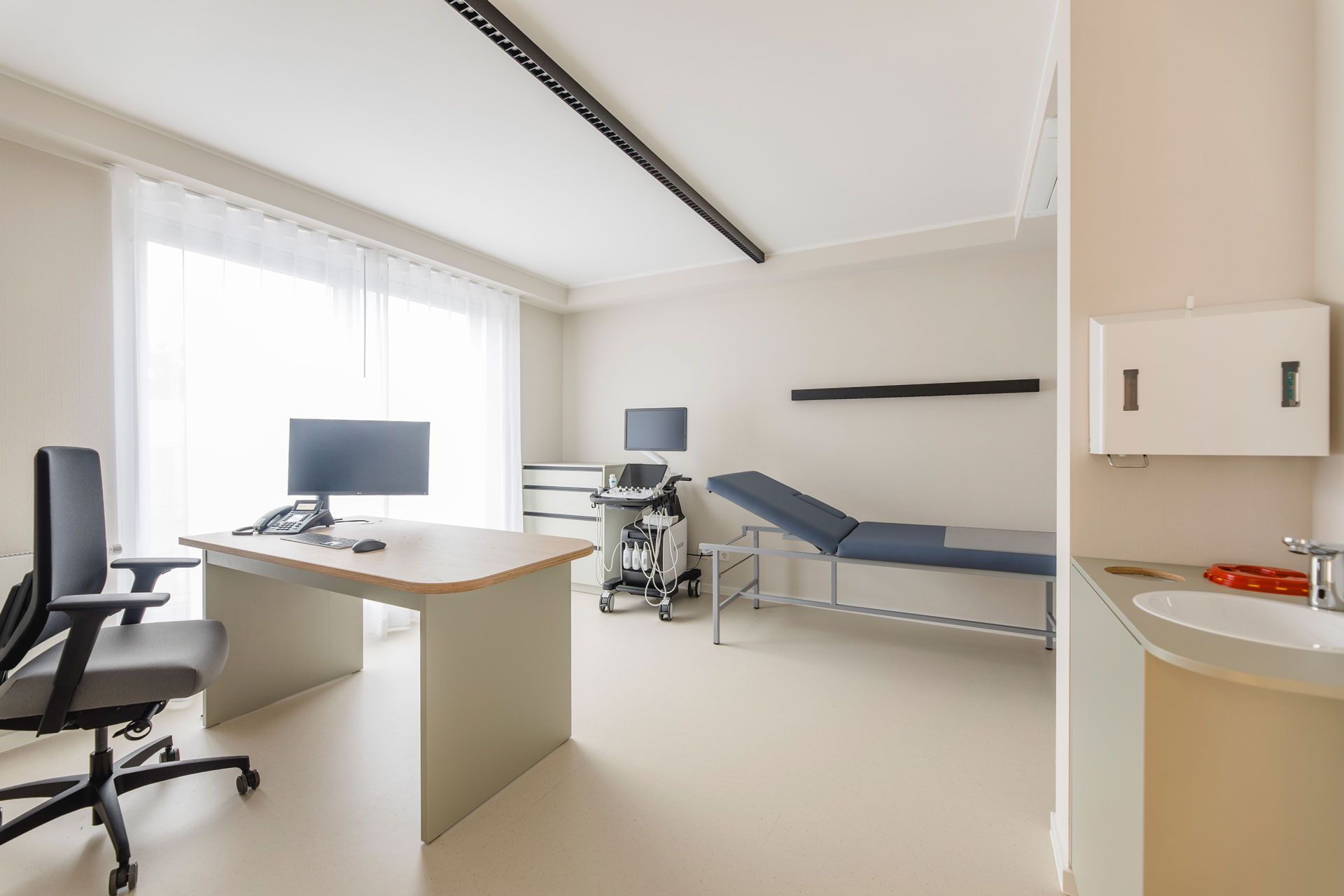 Besprechnugszimmer mit Schreibtisch und Liege und ein Ultraschallgerät
