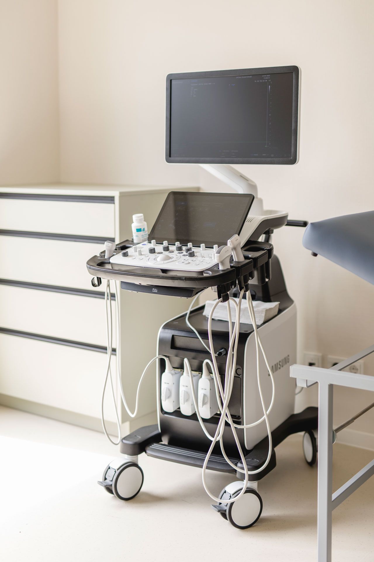 Ultraschallgerät in einem freundlichen neuen Behandlungszimmer zwischen Kommode und Liege
