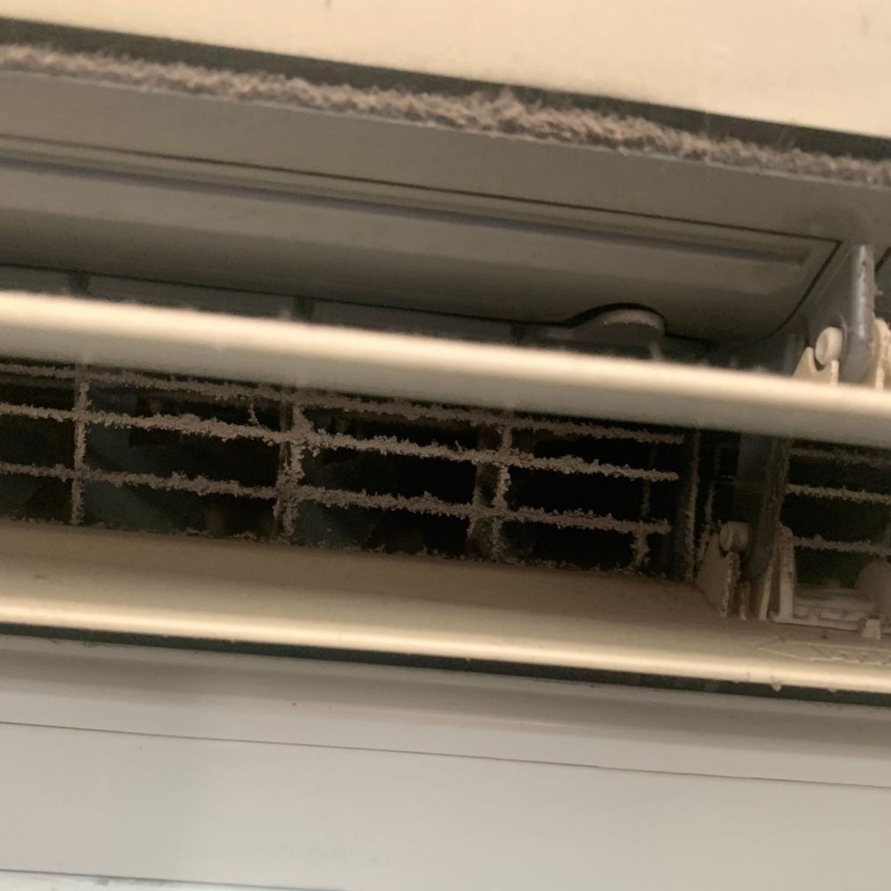 A close up of a dirty air conditioner on a wall.