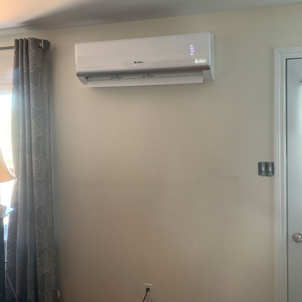 A white air conditioner is hanging on a wall in a living room.
