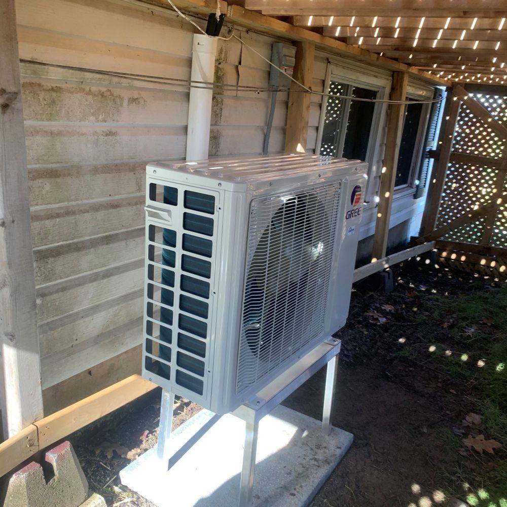 A large white air conditioner is sitting outside of a house.