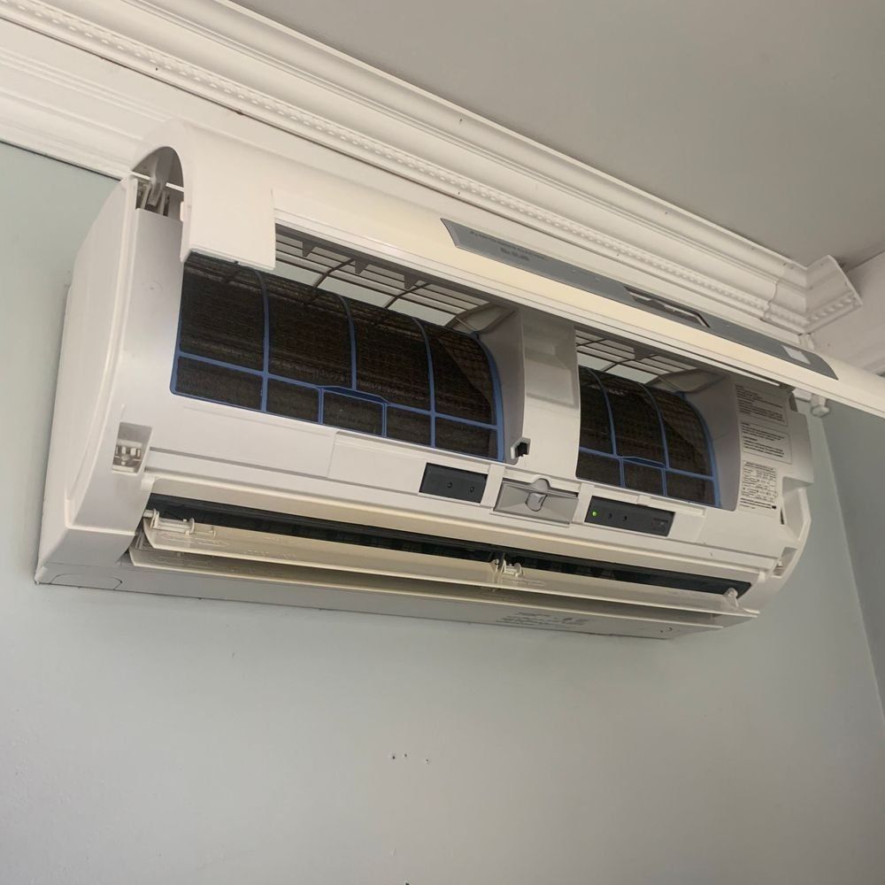 A white air conditioner is hanging from the ceiling in a room.