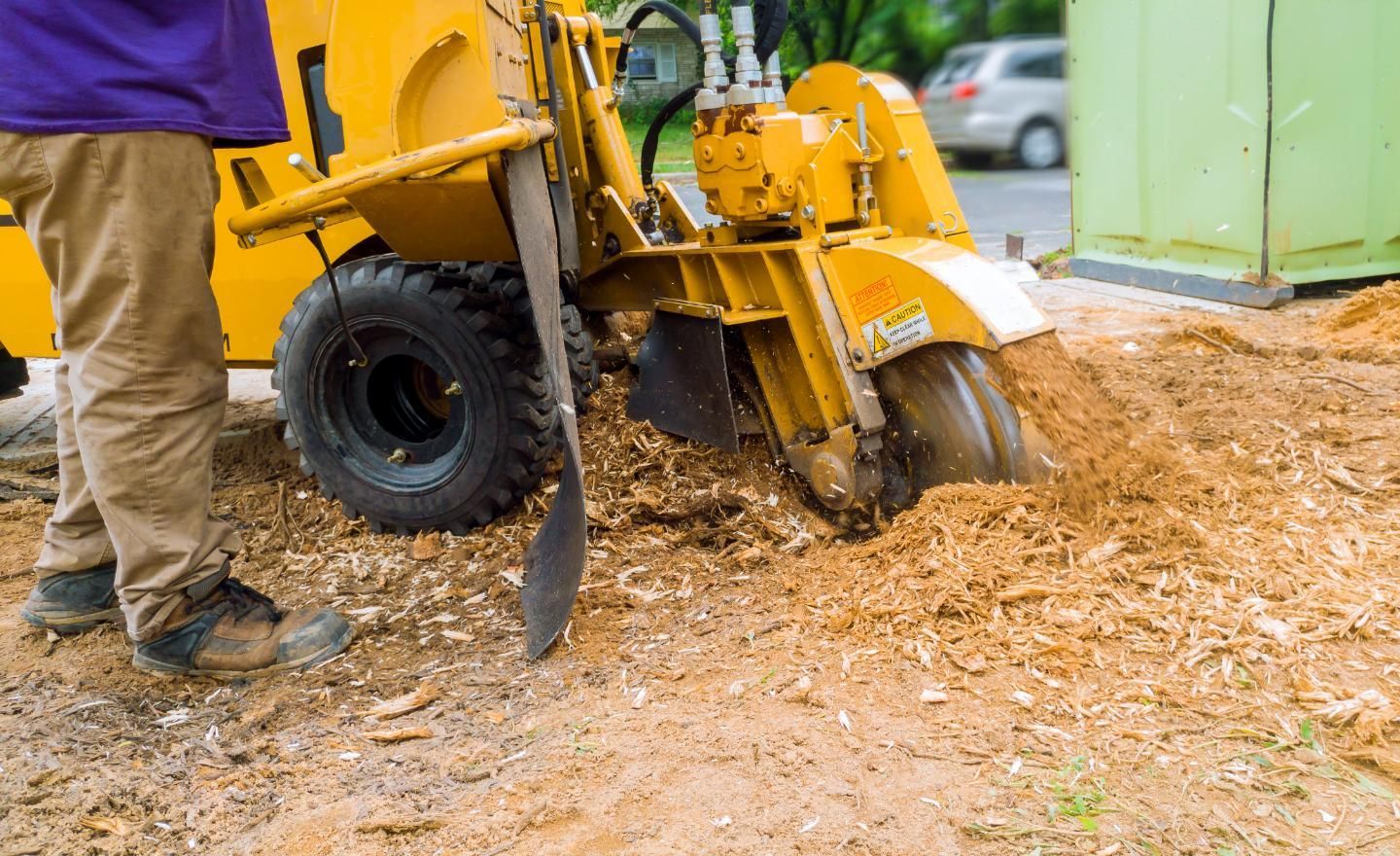 A man is using a stump grinder to remove a tree stump.