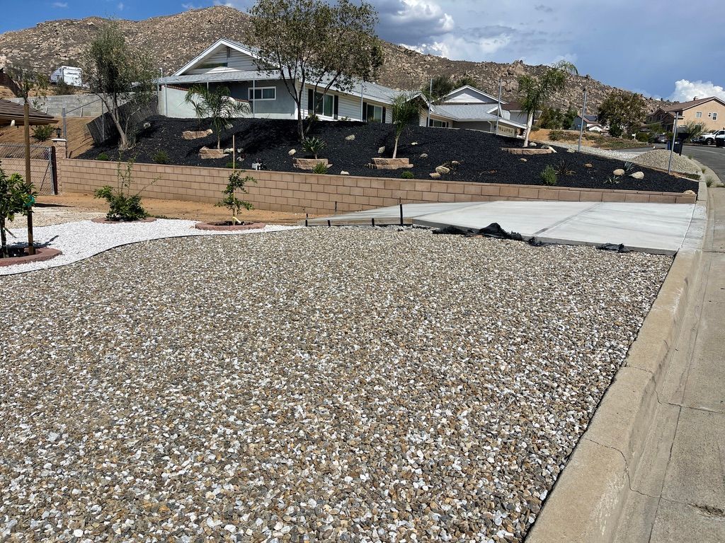 A house with gravel landscaping and a concrete driveway on a sunny day.
