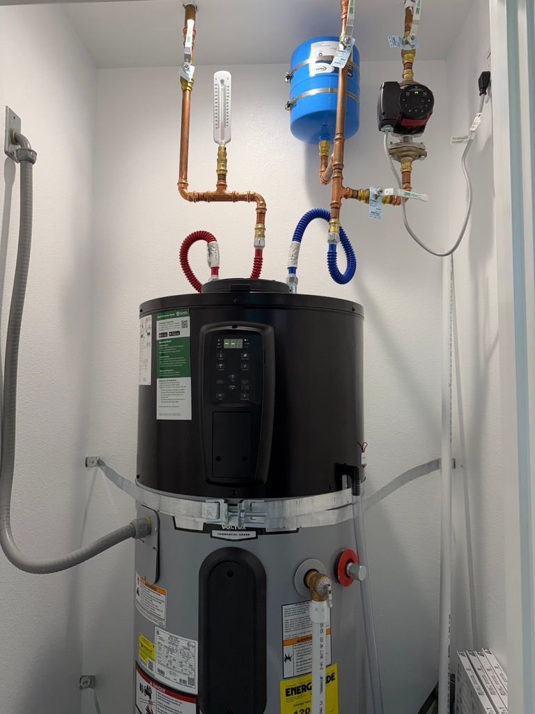 Water heater with copper pipes, pressure tank, and pump in a small utility room.