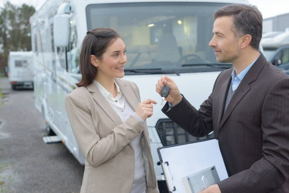 A man is giving a woman a key to a rv.