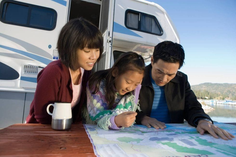 A family is looking at a map in front of a rv.